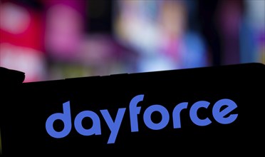 Dayforce logo is displayed on smartphone. Dayforce Inc provides HR software and services globally.