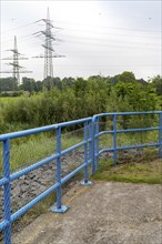 Blue metal railing in front of high voltage pylons