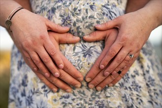 Couple forming a heart on belly bump in Albufeira, Algarve, Portugal, Europe