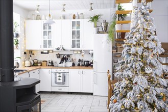 Festive Christmas decor in white kitchen, modern rustic interior with a snowy Christmas tree and