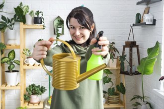 A portrait of a woman looks into the frame with an interior watering can and a spray gun for caring