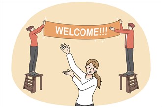 Happy people hanging Welcome banner inviting visitors to party or celebration. Smiling hosts