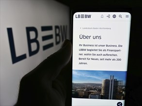 Stuttgart, Germany, 07-15-2024: Person holding cellphone with webpage of German company Landesbank