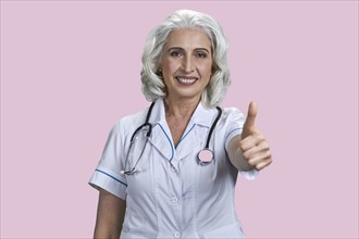 Successful senior woman doctor gesturing thumb up to camera. Joyful female doctor giving thumb up