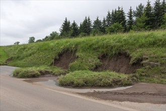 Symbolic image of climate change, slippery slope on a country road after heavy rainfall, near