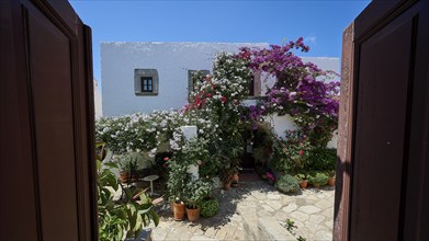 View through Tor tor into a flower-lined courtyard with white walls, Zoodochou Pigis Monastery, The