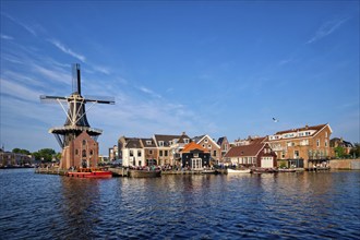 Harlem cityscape, landmark windmill De Adriaan on Spaarne river with boats. Harlem, Netherlands