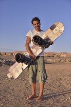 Man holding a sandboard, sandboarder, Sahara, Merzouga, Meknès-Tafilalet region, Morocco, Africa