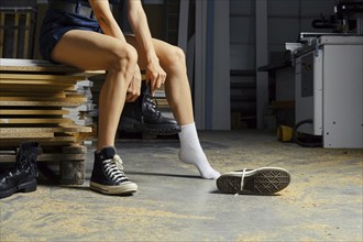 Female legs in carpenter shop, change of footwear