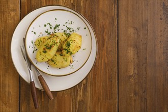 Top view of plate with hasselback potato on wooden table