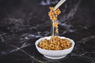 Traditional Japanese food Natto made from fermented soybeans drawing sticky strings on chopsticks