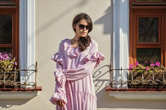 Outdoor urban portrait of young beautiful stylish girl in oversized pink dress