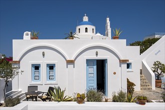 White house with blue door and church of Panagia Platsani, Ia, Oia, Santorini, Greece, Europe