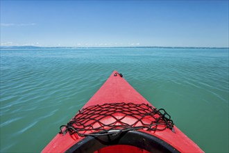 Bow of red kayak with view over the expanse and turquoise waters of Lake Constance