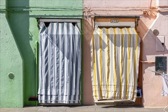 Green and pink house facade with entrance doors, colourful houses on the island of Burano, Venice,