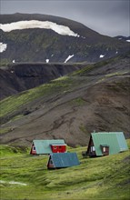 Cabins among volcanic landscape with black sand and green grass, Ásgarður, Kerlingarfjöll,