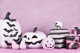 Pink Halloween decor with black and white pumpkins, spell books and spiders with copy space