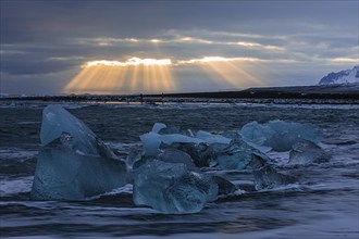 Waves breaking on icebergs on the black beach of Breidamerkursandur, sunset, near Jökullsarlon,