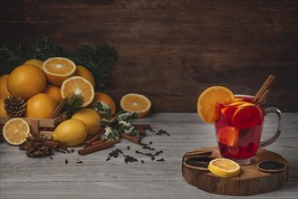 Wooden basket with oranges and lemons, punch in glass cup, cloves and cinnamon sticks, Christmassy,