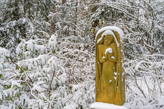 Gravestone with praying sculpture in the snow, Südwest-Kirchhof, historic cemetery in Stahnsdorf,