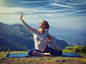 Yoga outdoors, young sporty fit woman doing stretching yoga asana Eka pada rajakapotasana,