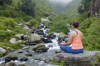 Woman doing yoga outdoors at waterfall