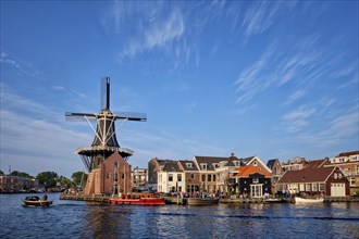 Harlem cityscape, landmark windmill De Adriaan on Spaarne river with boats. Harlem, Netherlands