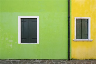 Green and yellow house facade with windows with closed shutters, colourful houses on the island of