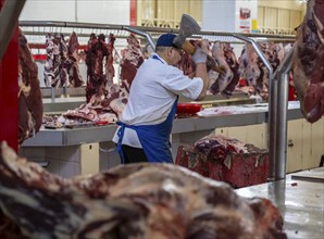 Man chopping meat and bones, butcher's shop with fresh meat, market at Osh bazaar, Bishkek,