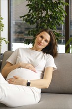 Beautiful pregnant woman having rest on sofa at home