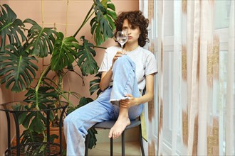 Woman with glass of mineral water sits by the window