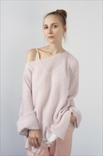 Pretty girl in thin angora sweater and slim pants posing near the wall