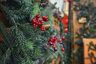 Close up of seasonal winter decoration of artificial red berries and pine branches at traditional