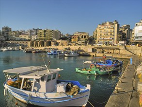 Morning light, fishing boats, old Venetian salt warehouse, houses, blue cloudless sky, harbour,