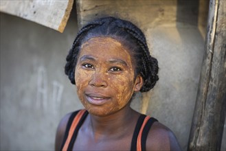 Close up portrait of Malagasy woman with sun protection mask made from the Musiro root in