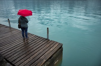 Older woman, best-ager, with red umbrella, bad weather, lakeside promenade at Lake Brienz, Brienz,