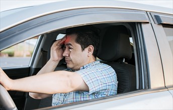 A driver with a headache in traffic, fatigued driver stuck in traffic, concept of a fatigued man in