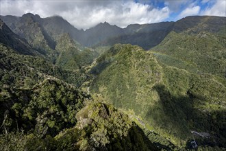 Densely overgrown steep mountains with rainbow, green mountain landscape, view from Miradouro dos