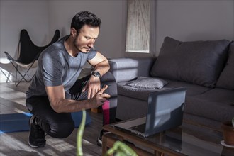 Latino fitness instructor teaching online in front of his laptop. Work at home, online training