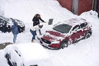 Women shovelling snow on car park, car, car, snowed in, fresh snow, heavy snowfall, snow masses,