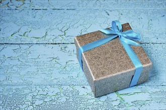 Gift birthday Christmas present concept, silver gift box with blue ribbon on blue painted wooden