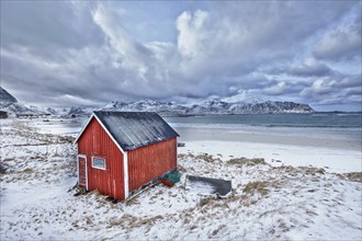 High Dynamic Range (HDR) image of red rorbu house shed on beach of fjord. Skagsanden beach, Lofoten