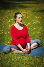 Pregnancy yoga exercise, pregnant woman doing asana baddha konasana bound angle pose outdoors on