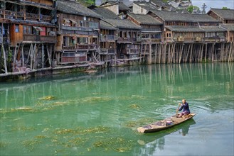 FENGHUANG, CHINA, APRIL 23, 2018: Unidentified chinese man in boat Feng Huang Ancient Town (Phoenix