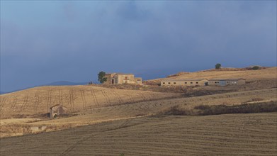 Dry hilly landscape, fields, farmstead, building, blue cloudy sky, Madonie National Park, autumn,