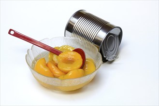 Peach, pickled peach halves in glass bowl with ladle and preserving tin