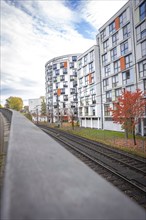 Modern residential complex next to railway tracks in autumn with blue sky in the background,