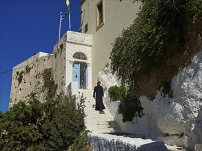 Stairs, young monk dressed in black on stairs, blue entrance door, Chrissoskalitissa, rock