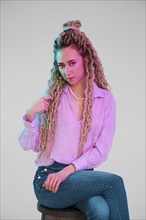 Young woman touching her dreadlocks and looking forward