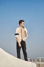 Full length portrait of a young man in unfastened white shirt on the street